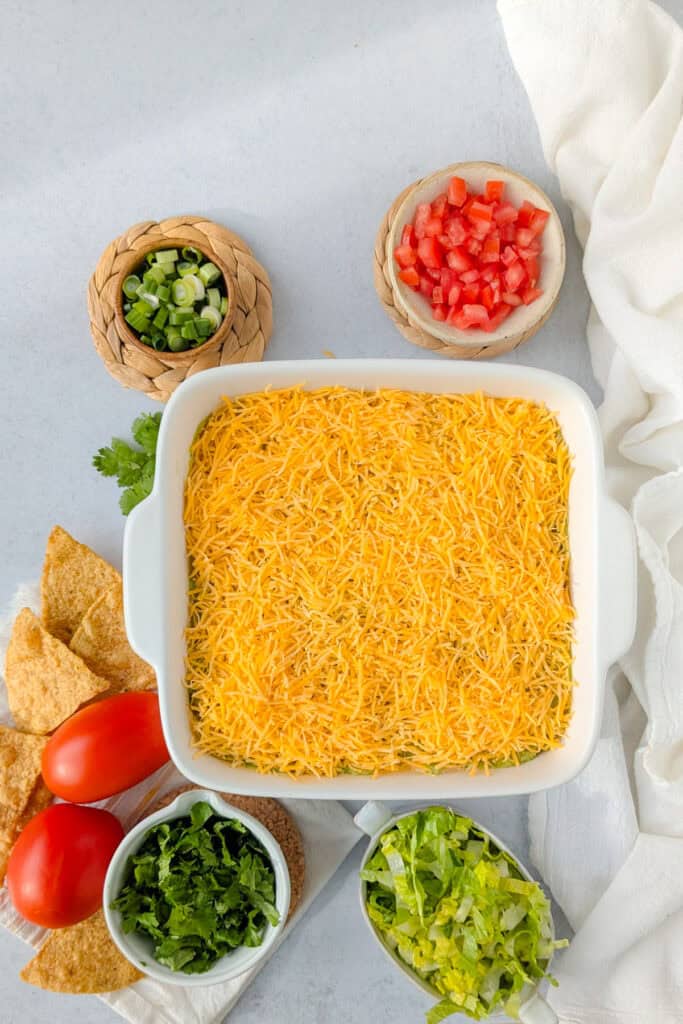 Overhead picture of 4 layer taco dip topped with shredded cheddar cheese. 