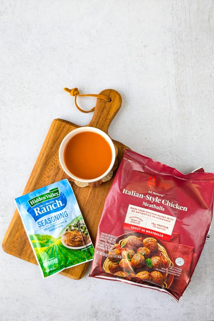 Overhead picture of all the ingredients needed to make this appetizer recipe. Good & Gather frozen chicken meatballs, Hidden valley ranch seasoning packet, and buffalo sauce. 