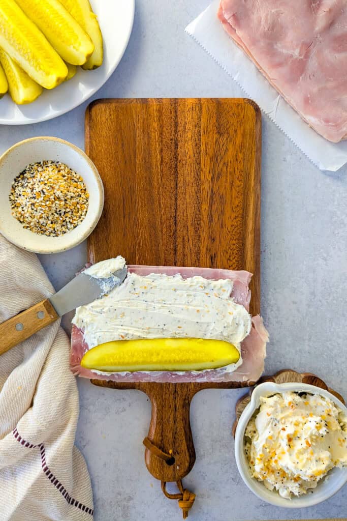 Overhead picture of cream cheese spread evenly over ham topped with a pickle spear. 