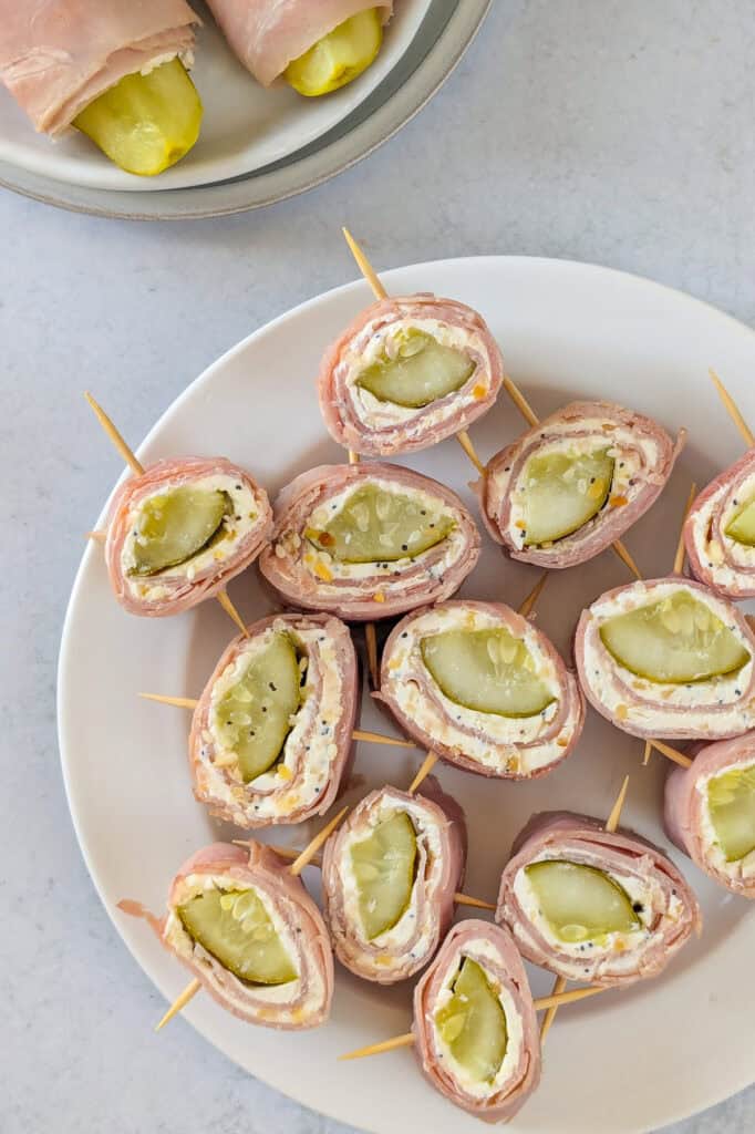 Overhead picture of dill pickle pinwheels on a white plate inserted with toothpicks. 