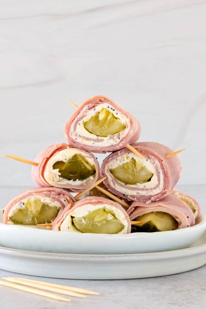 Picture of sliced pickles stacked on a plate inserted with toothpicks. 