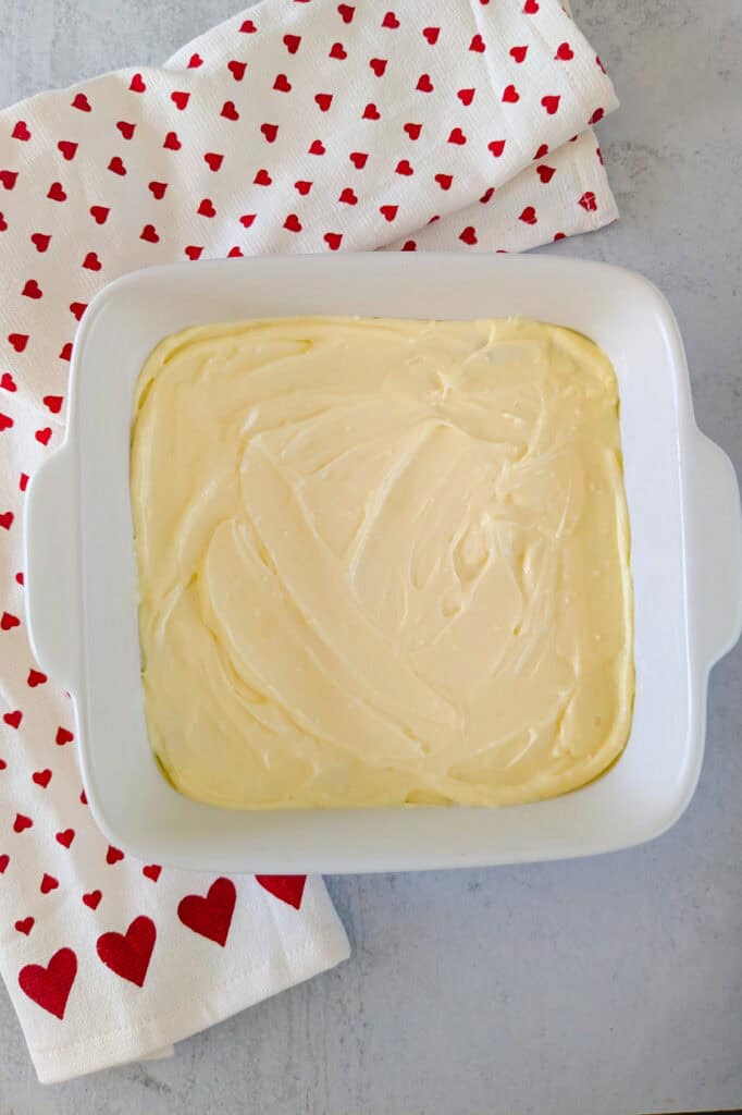 Overhead picture of brownies with cheesecake layer evenly spread over-top. 