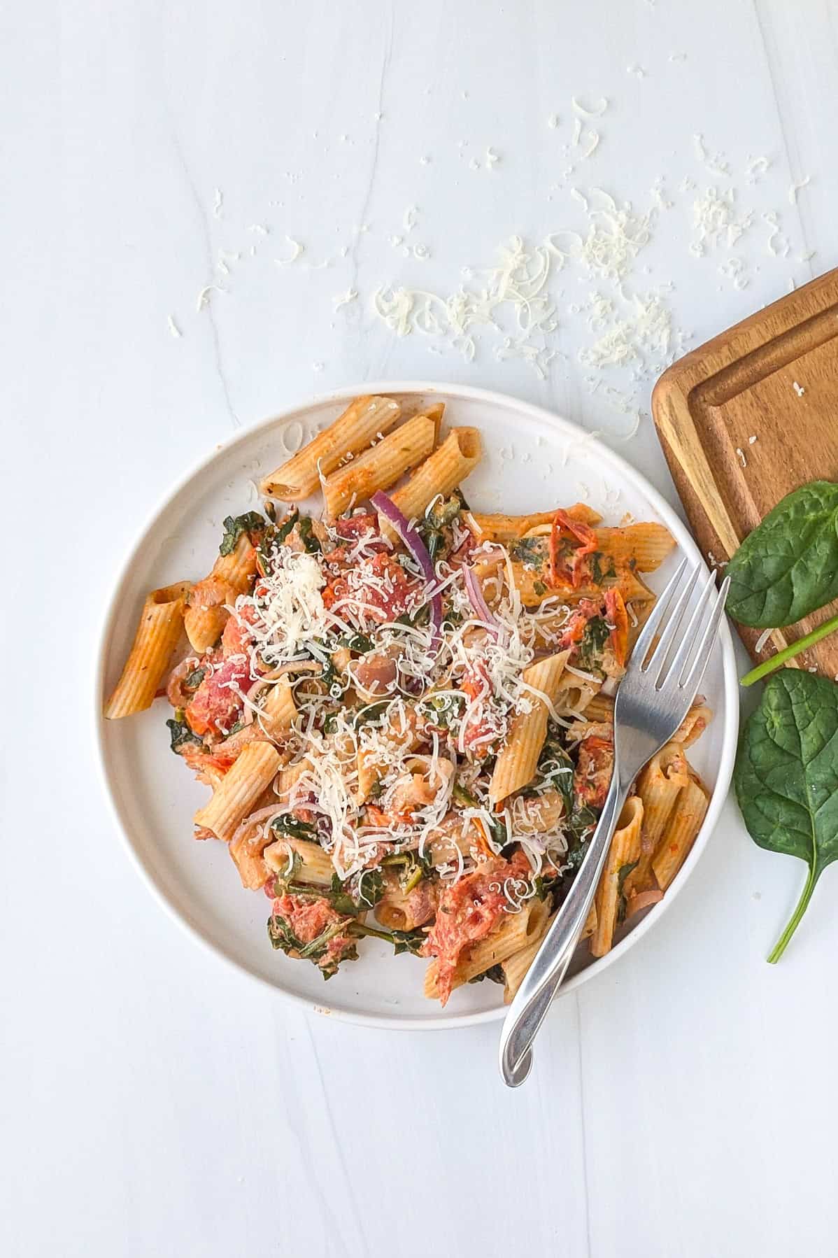 Overhead picture of baked Boursin cheese pasta on a white plate topped with grated Parmesan cheese.