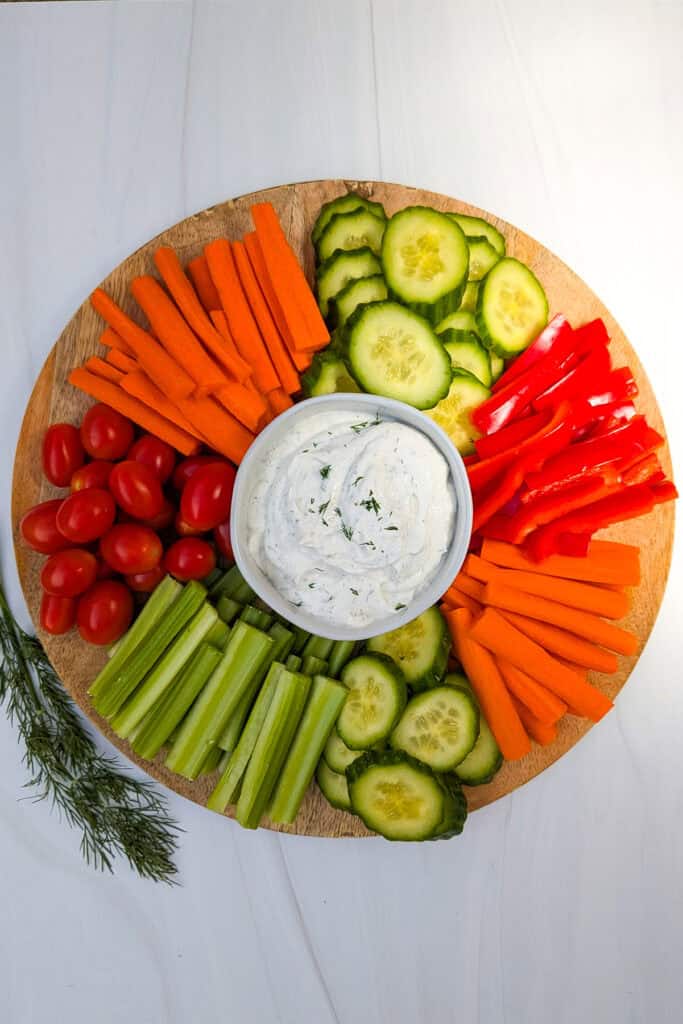 Overhead picture of Greek yogurt veggie dip on a serving tray with fresh vegetables for dipping. 