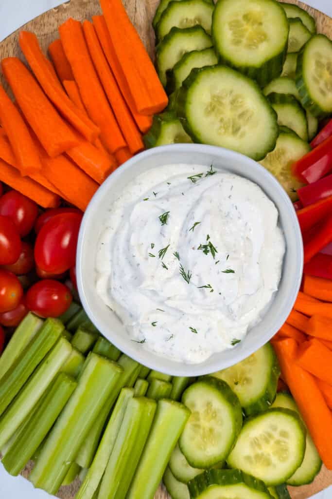 Up close overhead picture of Greek yogurt dip on a serving tray arranged next to fresh vegetables. 