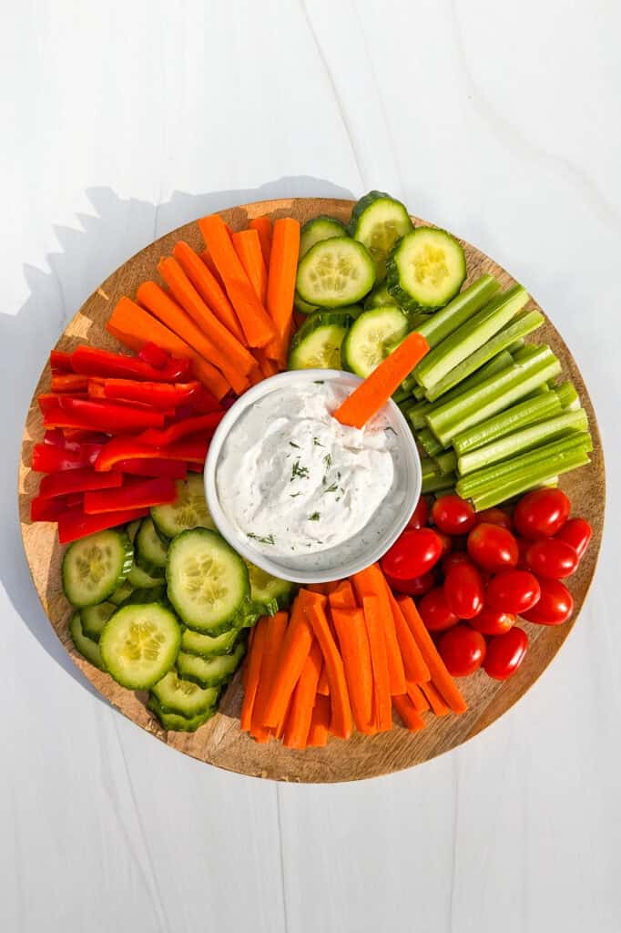 Overhead picture of Greek yogurt veggie dip on a serving platter with an assortment of fresh veggies. 