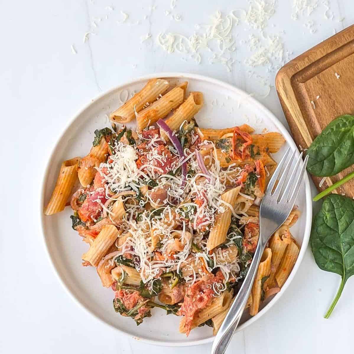 Overhead picture of baked Boursin cheese pasta on a white plate topped with grated Parmesan cheese.