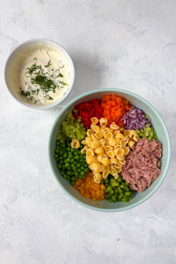 Overhead picture of dressing in a white bowl and all other ingredients in a bowl ready to be stired.