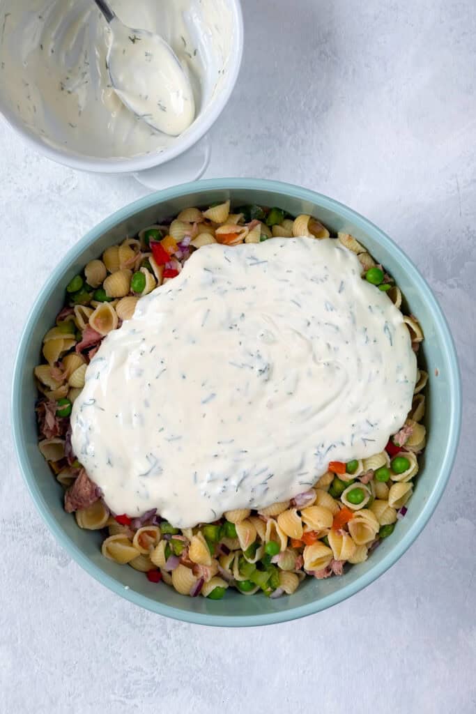 Overhead picture of dressing poured over-top tuna pasta salad.