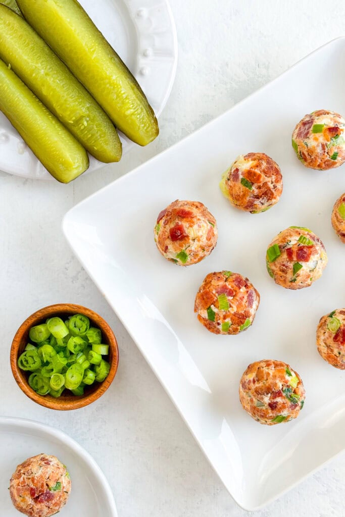 Overhead picture of bite-sized pickle bombs, dill pickles, and chopped green onions.