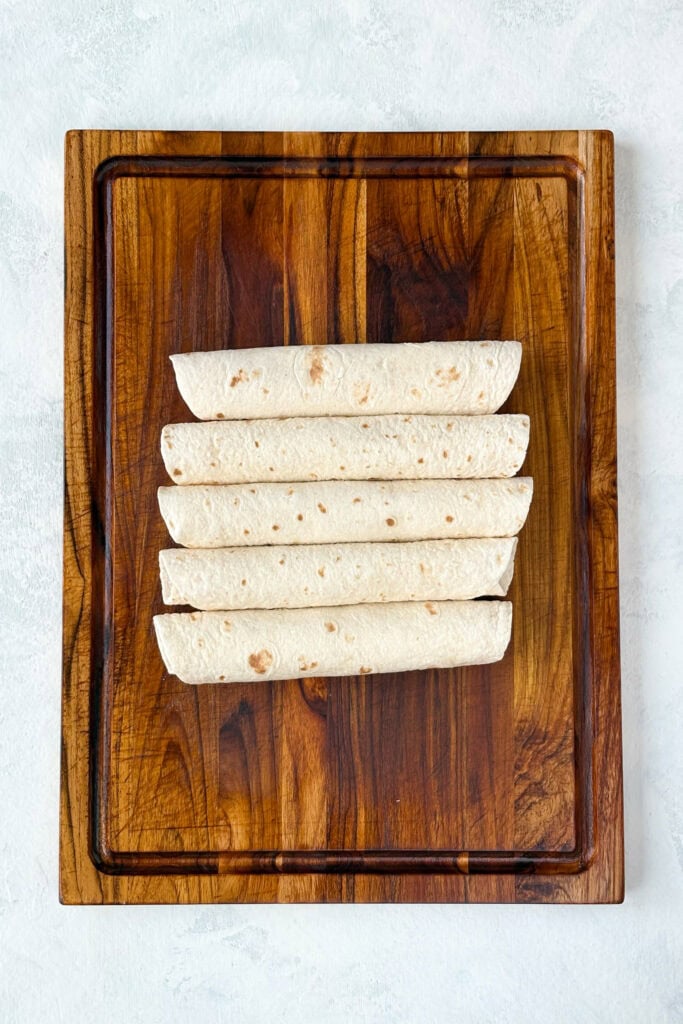 Overhead picture of pickle dip wraps rolled into 5 flour tortillas.